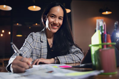 Portrait of a smiling young woman sitting on table