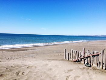 Scenic view of beach against clear blue sky