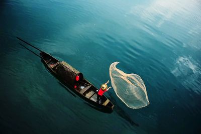 High angle view of man on boat throwing fishing net