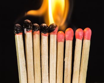 Close-up of burning matchsticks against black backgrounds
