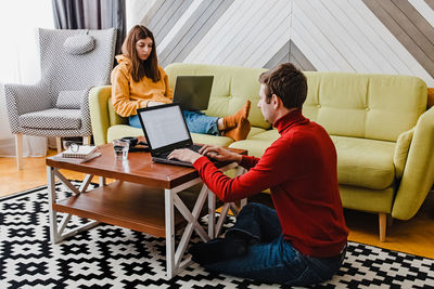 Young couple working at home in the living room. remote work, freelance, modern lifestyle.