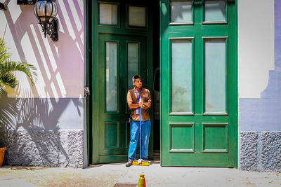 Portrait of smiling young woman standing against door