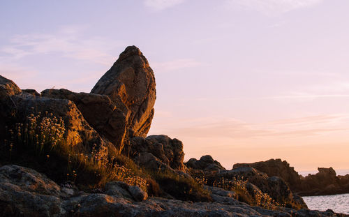 Rock formations by sea against sky during sunset