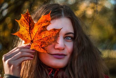 Close-up of young woman with autumn leaves