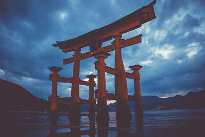 View of cross on lake against cloudy sky