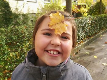 Close-up portrait of smiling girl with autumn leaf