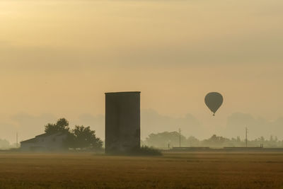 Hot air balloon flying over field during sunset