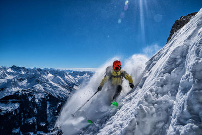 Woman skiing on snowcapped mountain against sky