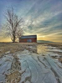 Snow covered land against sky during sunset