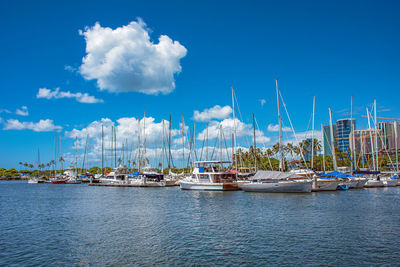 Kewalo basin marina in honolulu, hawaii, white clouds adorn the backdrop of a tranquil blue sky.