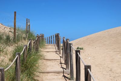 Empty steps at beach against clear blue sky