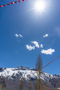 Low angle view of snowcapped mountains against blue sky on sunny day