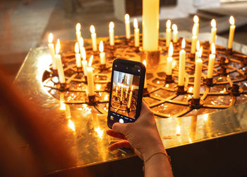 Cropped hand of woman holding illuminated candle
