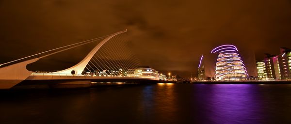 Illuminated bridge over river at night