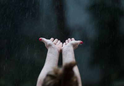 Rear view of woman cupping hands in pouring rain