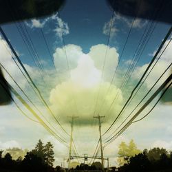 Low angle view of electricity pylon against cloudy sky