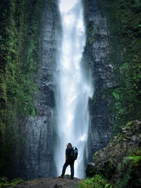 Man standing on rock against waterfall