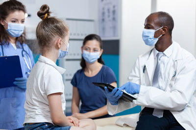 Doctor wearing mask examining girl in clinic