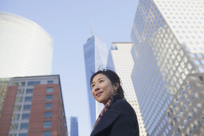 Young asian businesswoman looking up at skyline of big city