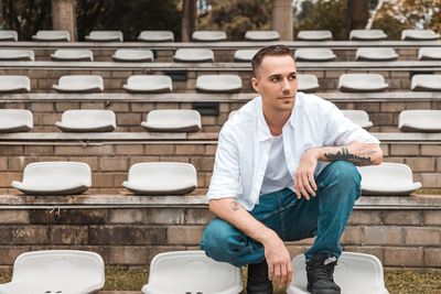 Young man squatting on patterned sitting area