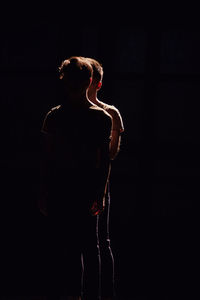 Side view of woman looking up against black background