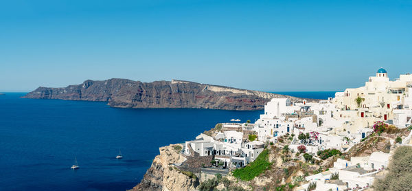 Panoramic view of oia town in santorini island with old whitewashed houses and traditional windmill.