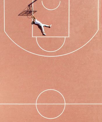 High angle view of man lying on court by basketball hoop shadow