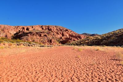 Scenic view of desert against clear blue sky