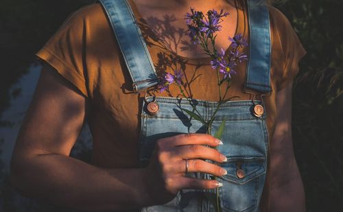 Midsection of woman holding purple flowers