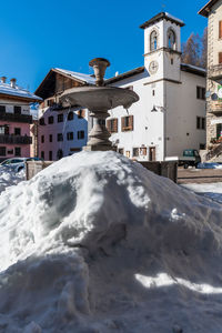 Snow covered buildings against blue sky