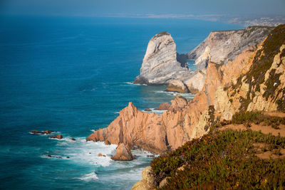 Rock formations by sea against blue sky