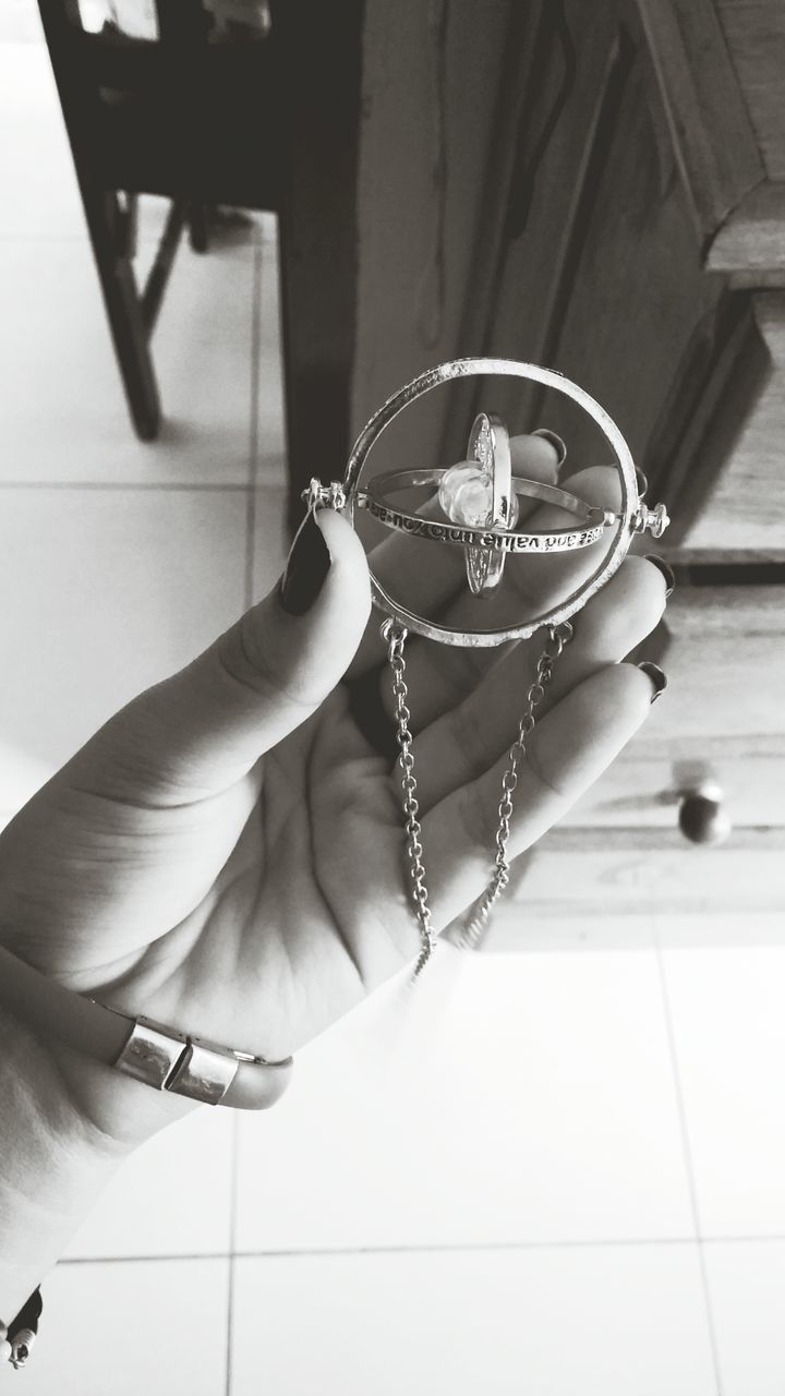 person, holding, indoors, part of, lifestyles, cropped, human finger, leisure activity, close-up, unrecognizable person, focus on foreground, front view, table, home interior, bracelet, ring