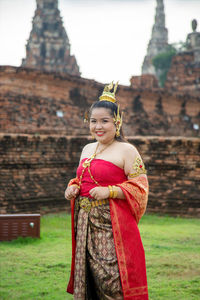 Portrait smiling asian woman in a thai dress with an old pagoda background