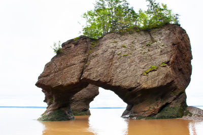 Rock formation in sea against clear sky