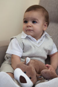 Cute toddler boy sitting on chair at home