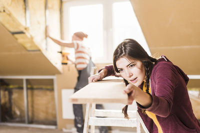 Young woman checking plank on construction site