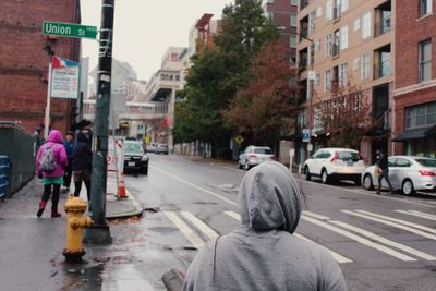 Rear view of people walking on road in city