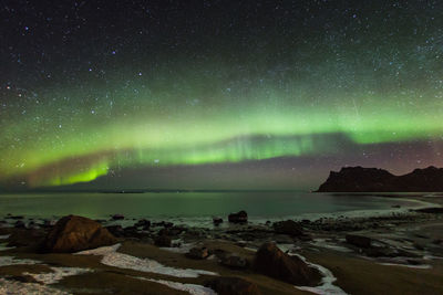 Scenic view of sea against aurora borealis at night