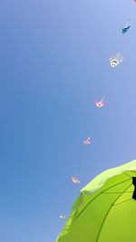 Low angle view of kites against clear blue sky