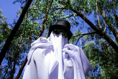 Low angle view of person against trees in forest