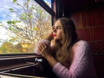 Thoughtful woman looking through window while traveling in train