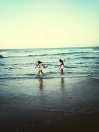 Men standing on beach against clear sky