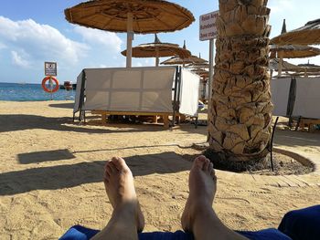 Low section of people on beach against sky
