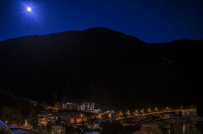 Illuminated buildings in town against clear sky at night