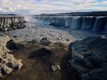 Scenic view of waterfall against sky