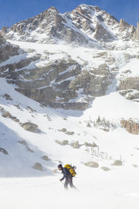 Woman hikes across frozen black lake, rocky mountain national park