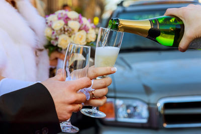 Cropped hand pouring champagne in glass held by bride