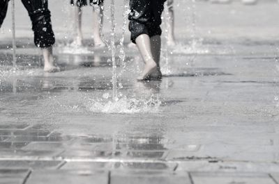 Low section of children playing at fountain on street