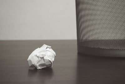 Close-up of crumpled paper and garbage can on table