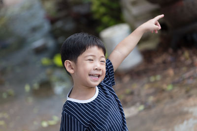 Smiling cute boy gesturing while standing outdoors